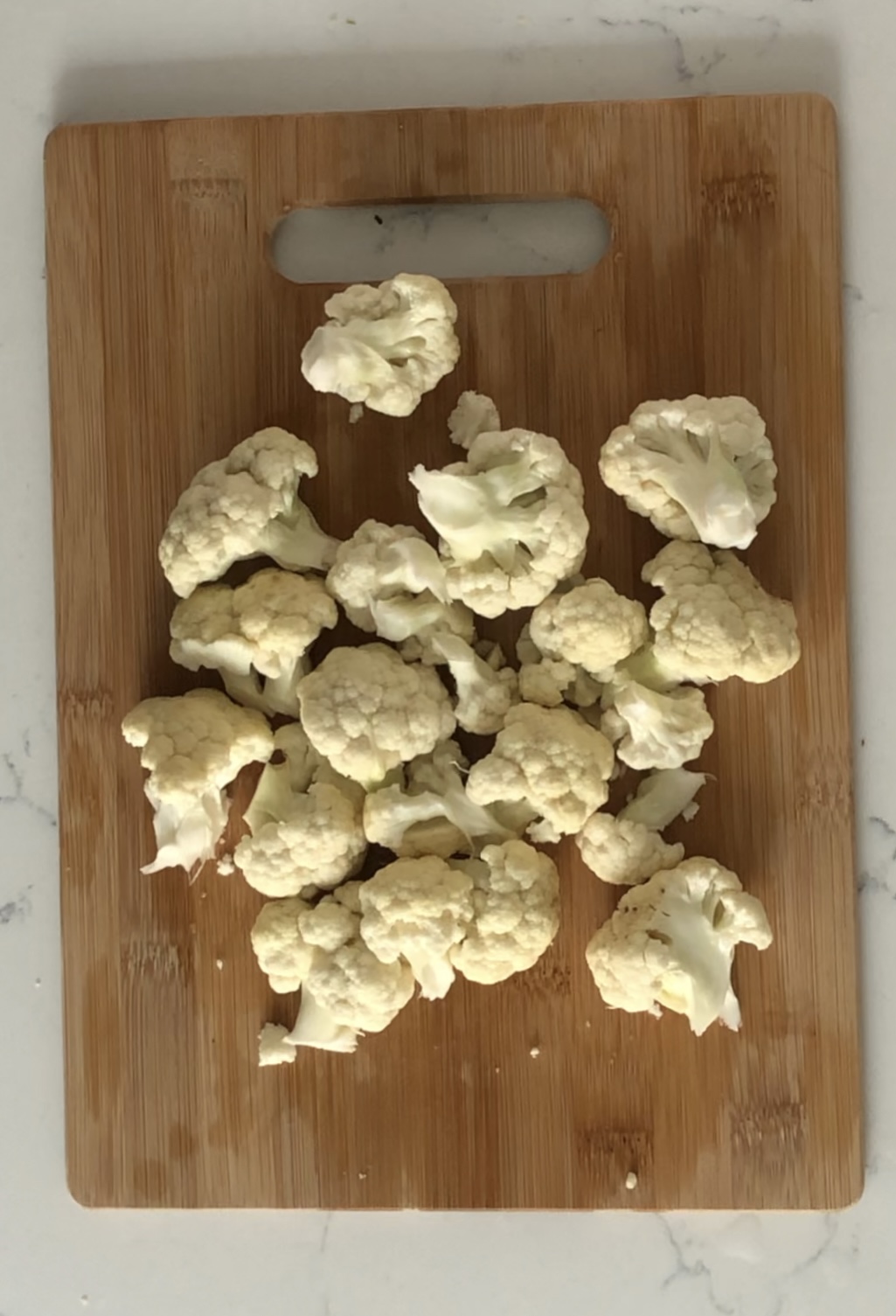 cauliflower florets on wood cutting board